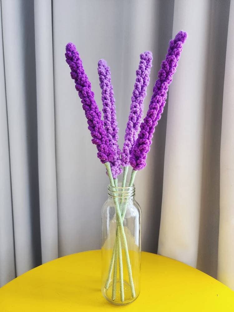 Crocheted lavender flowers in glass vase on yellow table