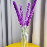 Crocheted lavender flowers in glass vase on yellow table