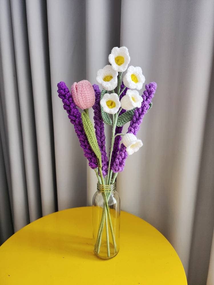 Crocheted flower bouquet in a glass vase on a yellow table