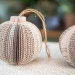 Two paper book page Christmas ornaments.
