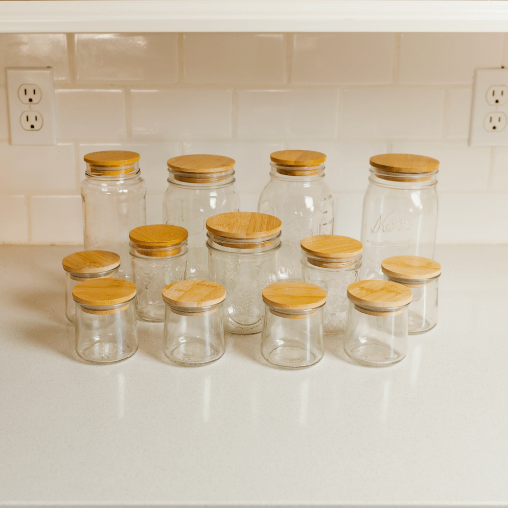Glass jars with wooden lids on a white countertop.
