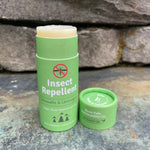 Green insect repellent stick and cap on stone.