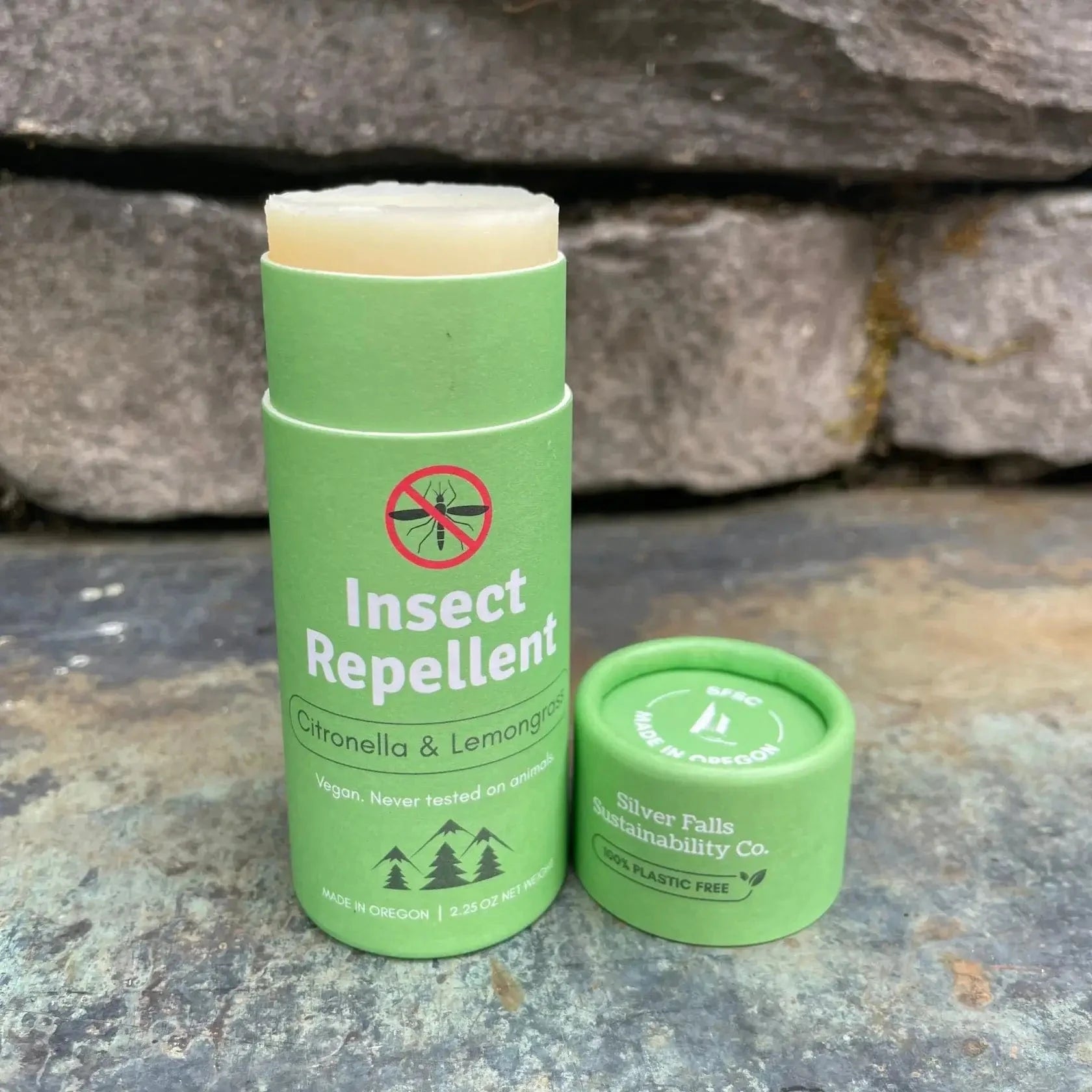 Green insect repellent stick and cap on stone.