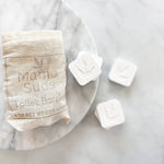 Bag of toilet bombs and three individual tablets on marble.