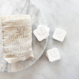 Bag of toilet bombs and three individual tablets on marble.