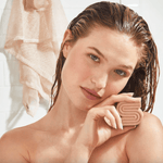 Woman with wet hair holding a pink soap.