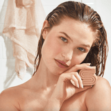 Woman with wet hair holding a pink soap.