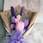 Crocheted bouquet of flowers wrapped in paper and tied with a purple bow.