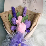 Crocheted bouquet of flowers wrapped in paper and tied with a purple bow.