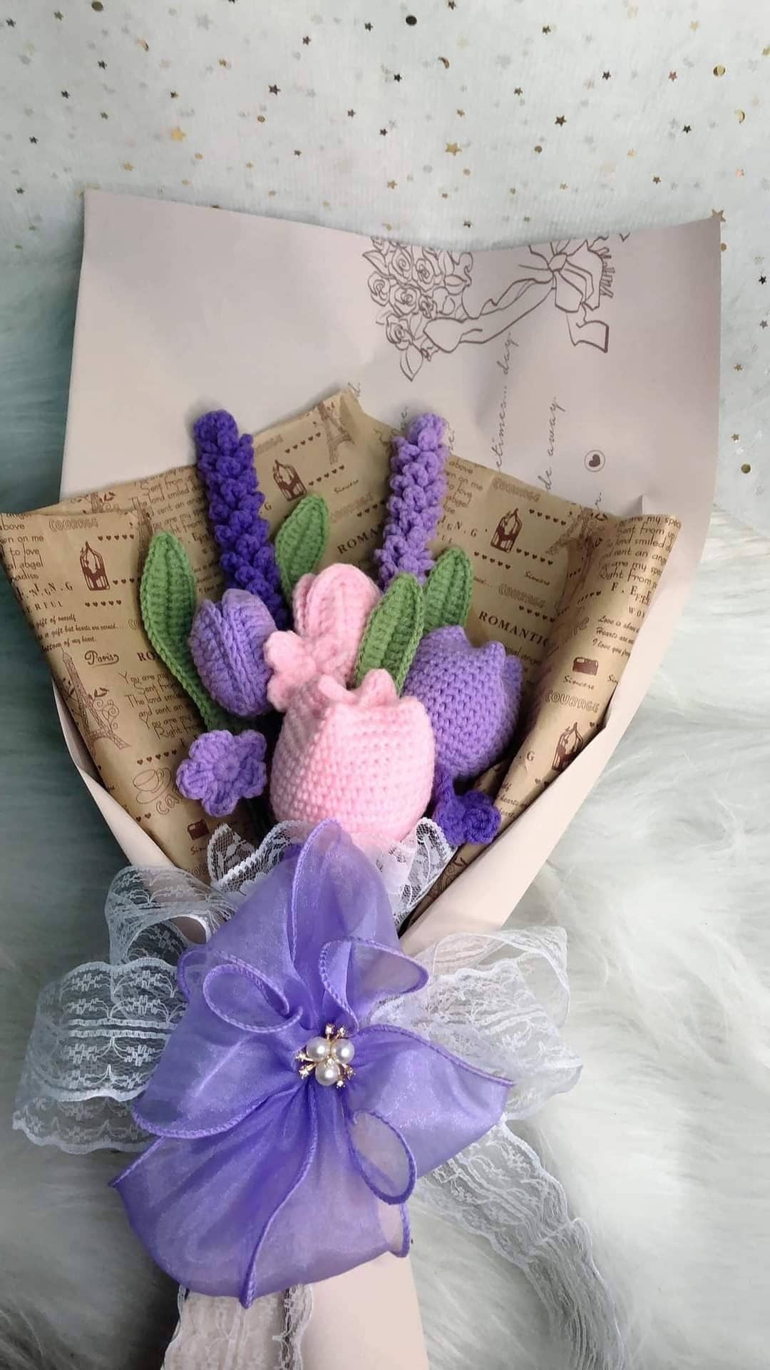 Crocheted bouquet of flowers wrapped in paper and tied with a purple bow.