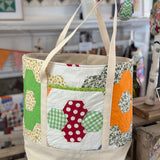 Quilted tote bag with colorful patchwork hexagons.