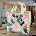 Pink patchwork tote bag with cream handles.