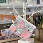Quilted pink and patterned clutch with wrist strap.