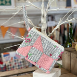 Quilted pink and patterned clutch with wrist strap.