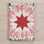Quilt with star pattern on a wooden surface, featuring red and white colors.
