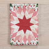 Quilt with star pattern on a wooden surface, featuring red and white colors.