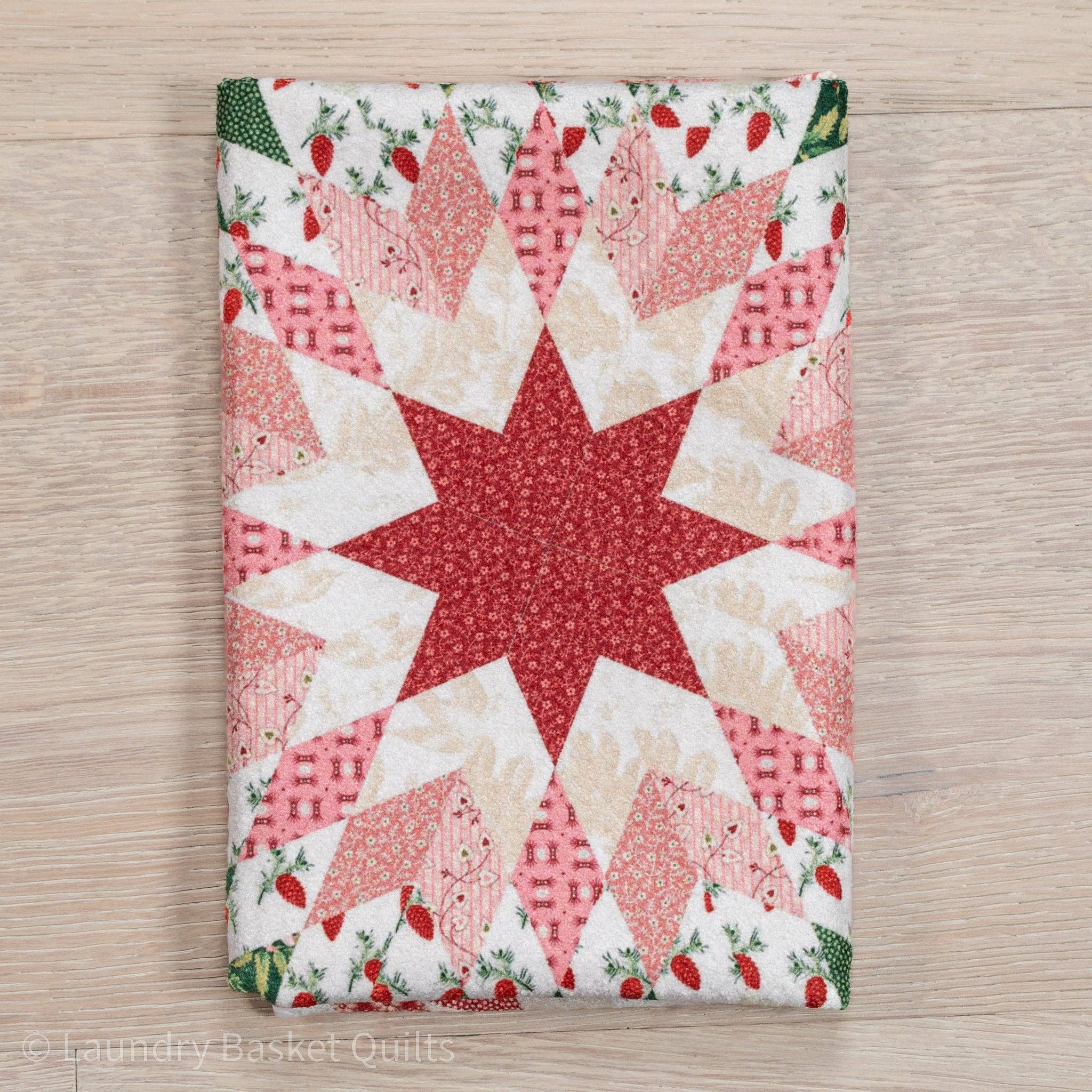 Quilt with star pattern on a wooden surface, featuring red and white colors.