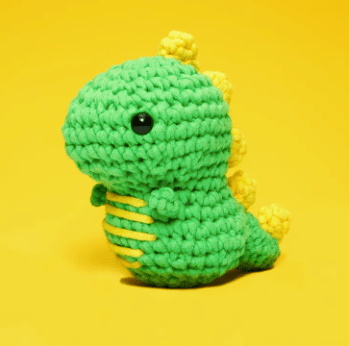 Crocheted green dinosaur toy on yellow background, screenshot from June 15