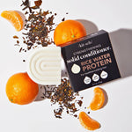 Solid conditioner, oranges, and tea leaves on a white surface.