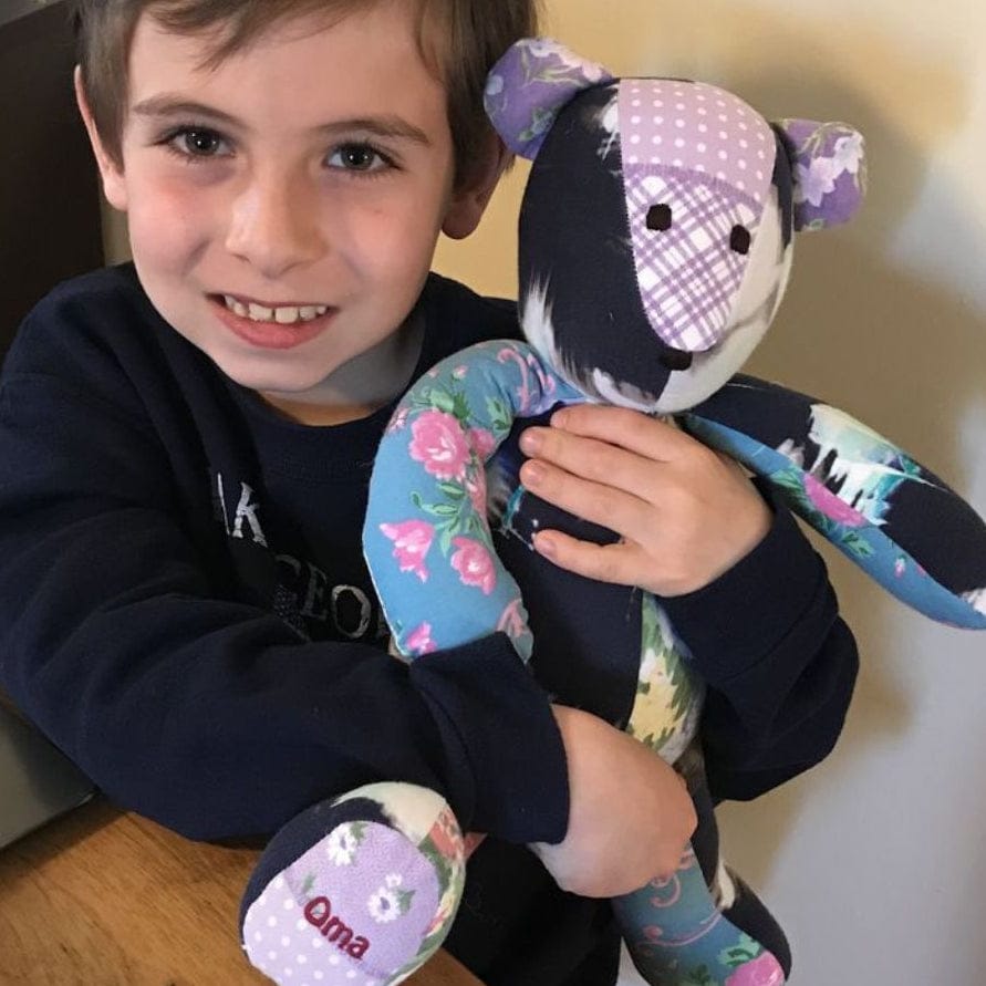Child holding a memory bear made with a grandmother's clothing