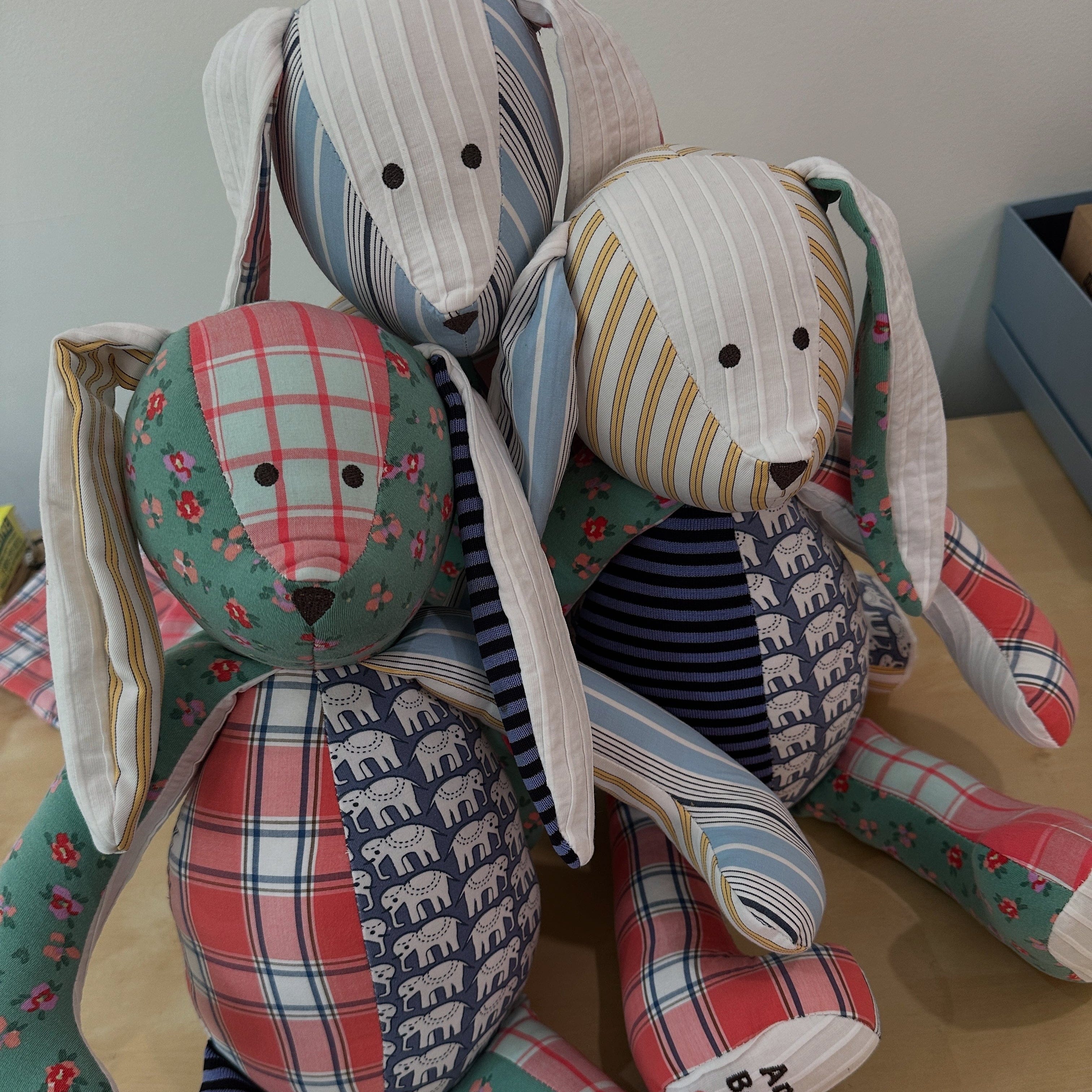 Three colorful fabric bunnies with patterned designs on a wooden surface.