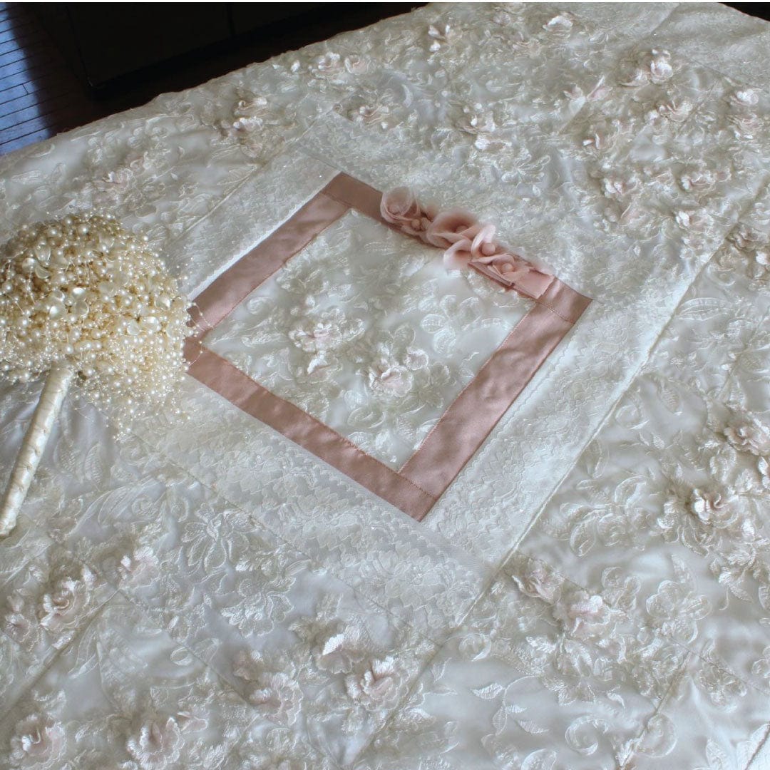 Blush wedding quilt center with ribbon and bouquet