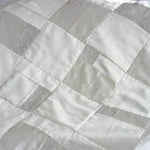 Close-up detail of white wedding quilt with beaded accents