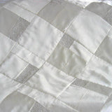 Close-up detail of white wedding quilt with beaded accents