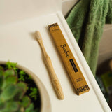 Bamboo toothbrush and packaging on a bathroom counter.