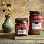 Two soy candles and a vase with flowers.
