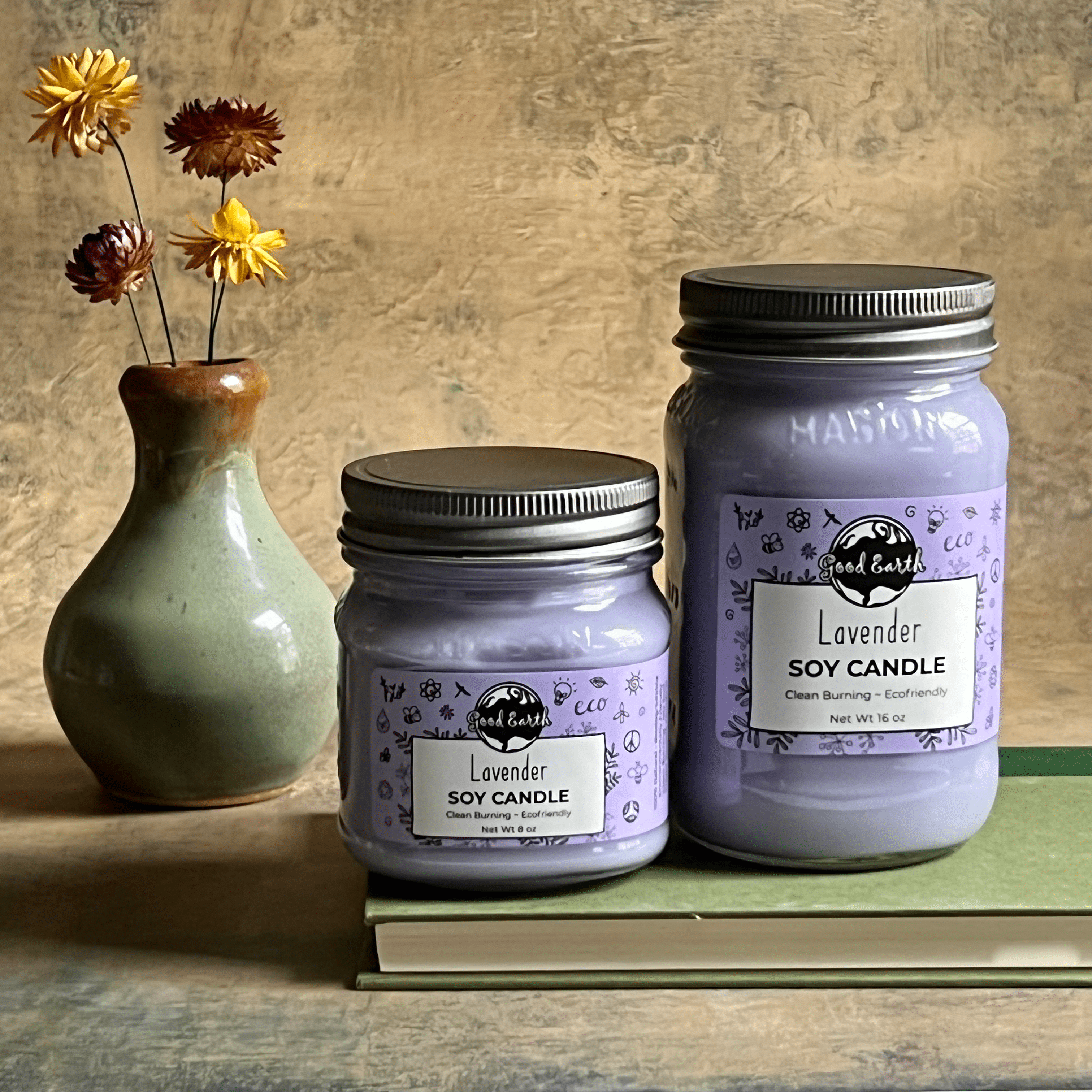 Two lavender soy candles and vase of flowers.