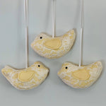 Three yellow lace bird ornaments.