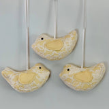 Three yellow lace bird ornaments.