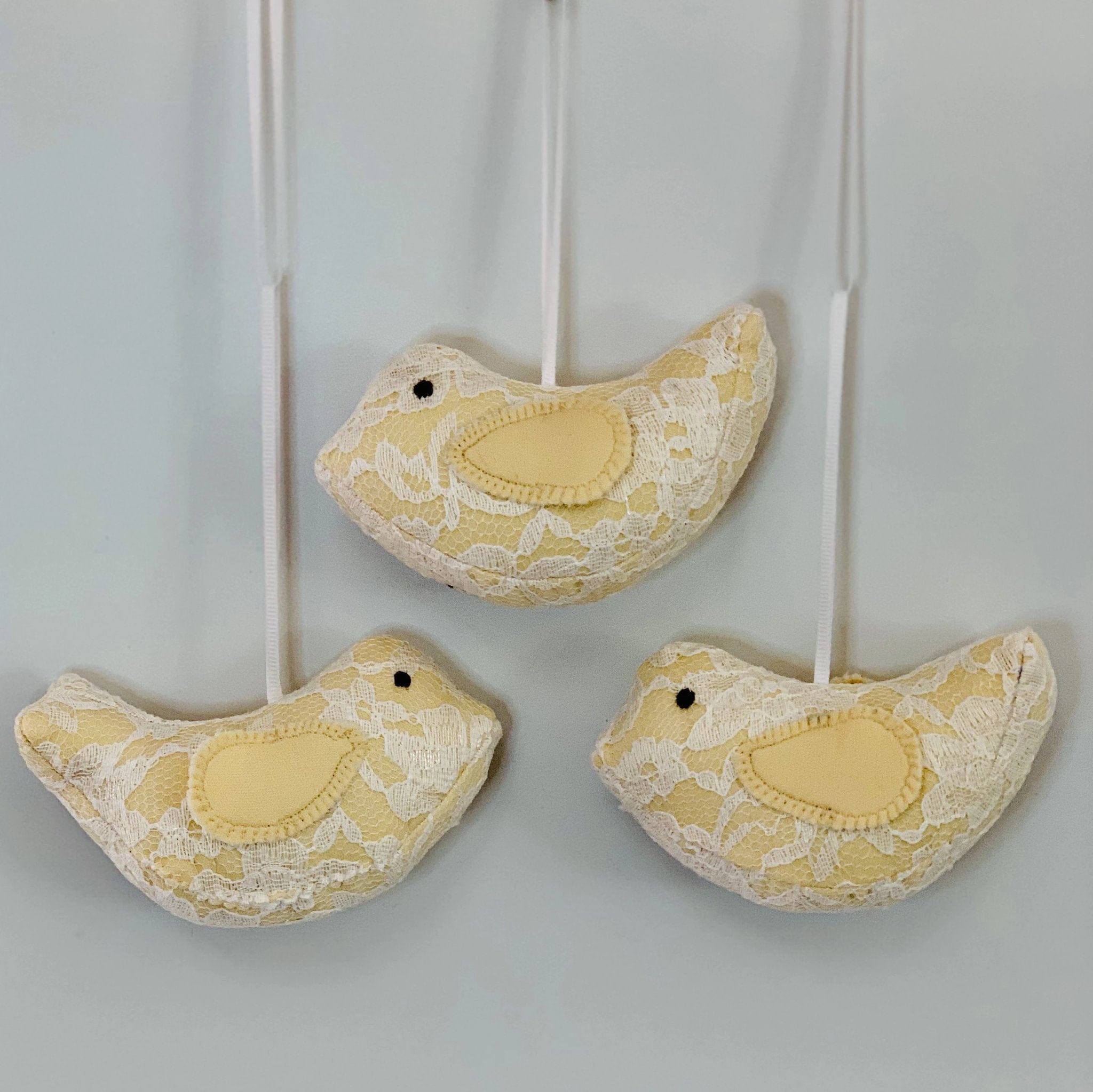 Three yellow lace bird ornaments.