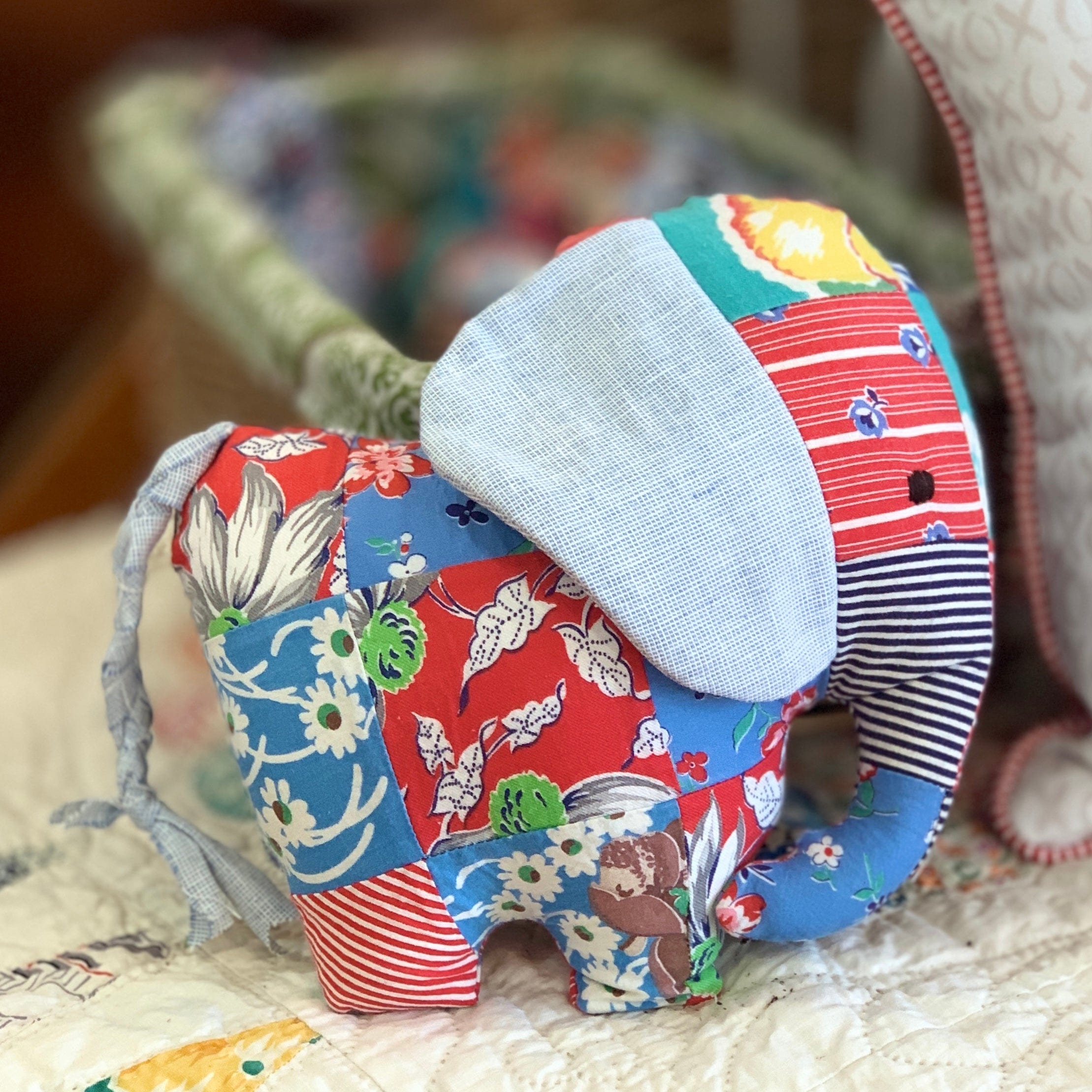 Stuffed patchwork elephant toy with a blue ear.