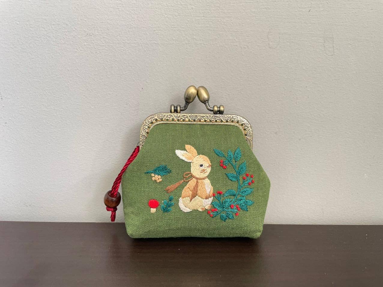 Green coin purse with embroidered bunny.