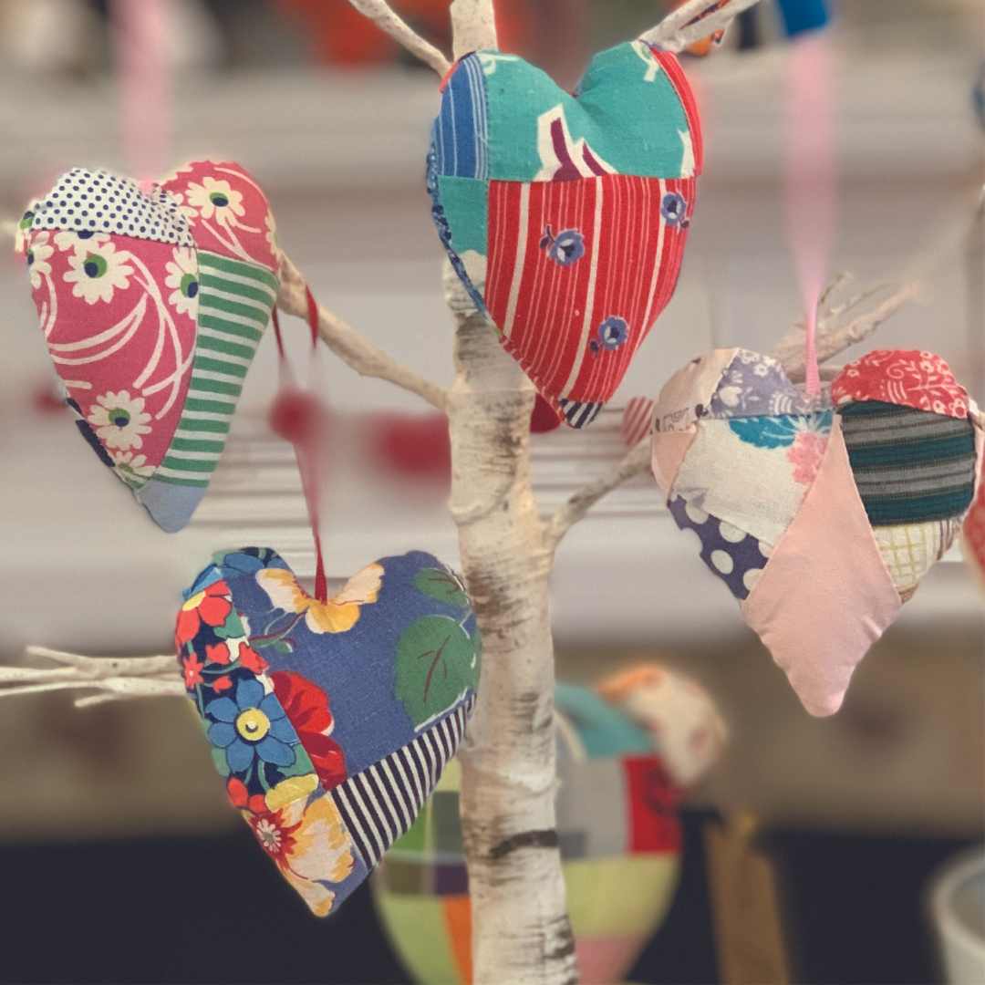 Patchwork heart ornaments hanging on a tree.